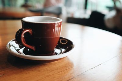 Close up view of a brown coffee cup on a wooden table in a coffee shop