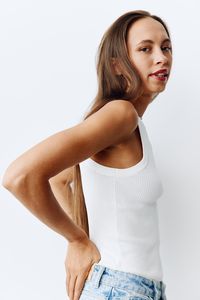 Portrait of young woman standing against white background