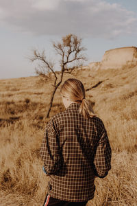 Rear view of woman standing on land against sky