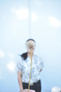 Woman standing on flowering plant against sky