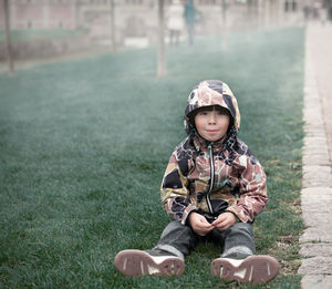 Portrait of cute boy sitting on grass