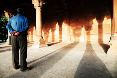 Full length rear view of man looking at red fort wall