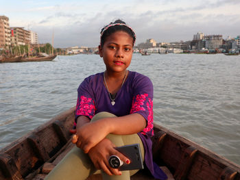 Portrait of mid adult girl sitting in river against sky