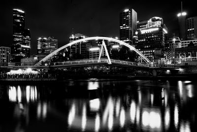 Illuminated bridge over river in city at night