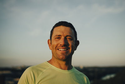 Portrait of smiling sportsman against sky during sunset