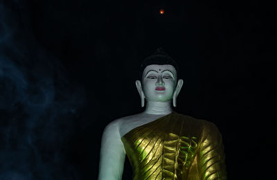 Statue of buddha against black background