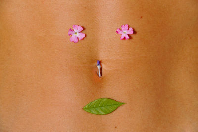 Midsection of woman with flowers and leaf on abdomen