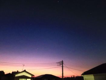 Low angle view of silhouette electricity pylon against sky at sunset