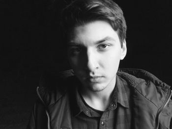 Close-up portrait of young man against black background