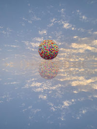 Digital composite image of balloons against sky