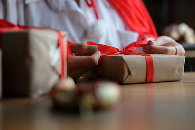 Midsection of woman holding red while sitting on table