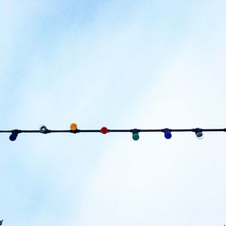 Low angle view of light bulbs hanging against clear sky