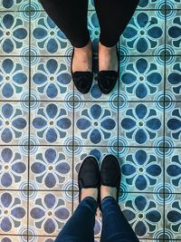 Low section of women standing on tiled floor