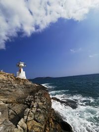 Lighthouse by sea against sky