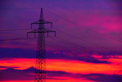 Low angle view of electricity pylon against dramatic sky