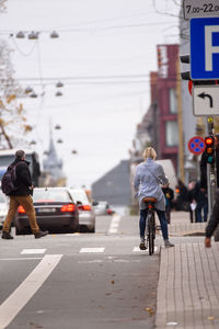 Rear view of men walking on road in city