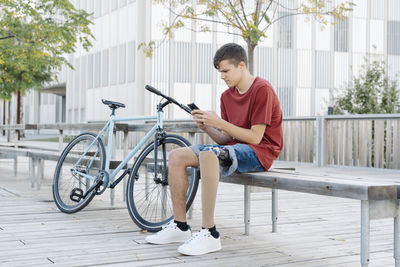 Man with disability using smartphone near bicycle