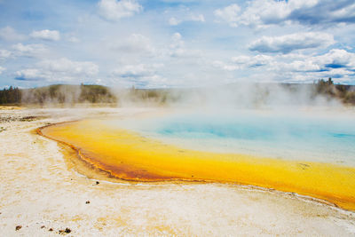 Scenic view of hot springs at yellowstone national park against cloudy sky