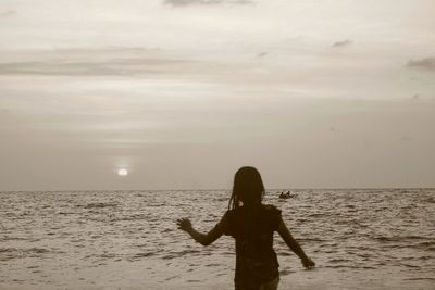 Rear view of woman standing on beach against sky