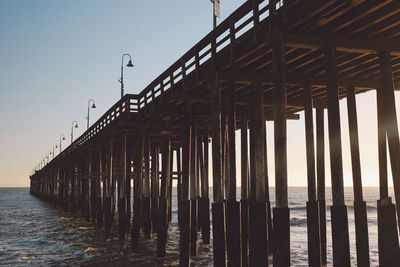 Silhouette pier over sea against clear sky