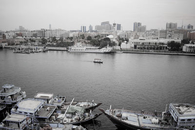 Boats moored in river by buildings in city against sky