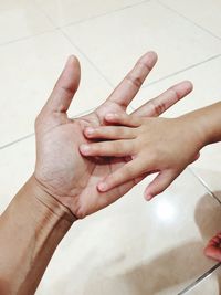 High angle view of cropped hands on tiled floor