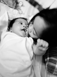 High angle view of girl kissing baby boy relaxing on bed at home