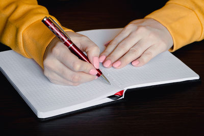 Midsection of man writing in book at table