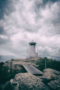 Low angle view of lighthouse by building against sky