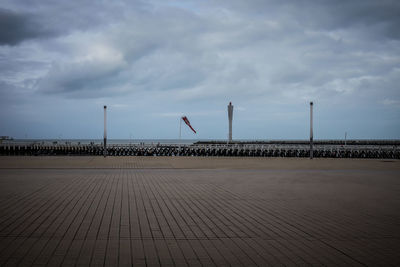 Empty promenade against cloudy sky