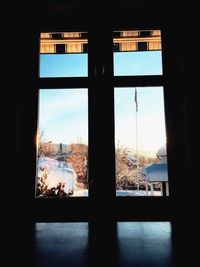 Silhouette landscape seen through window during winter