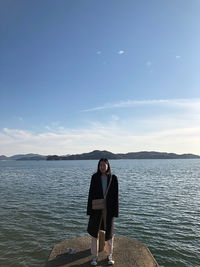 Full length of woman standing by sea