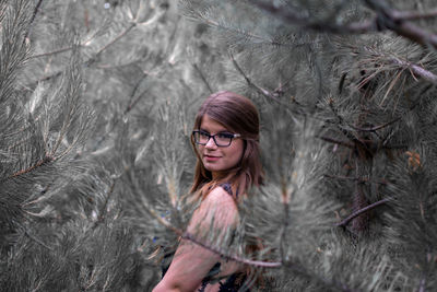 Portrait of young woman standing amidst plants