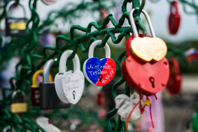 Close-up of heart shape padlocks hanging on metal against sky