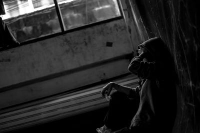 Side view of woman sitting at window