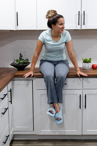 Hispanic woman sitting on a kitchen countertop