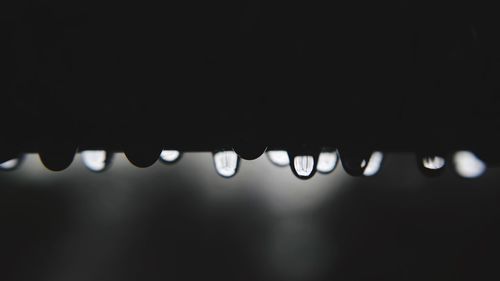 Close-up of water drops on roof against black background