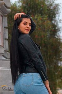 Portrait of young woman standing against trees