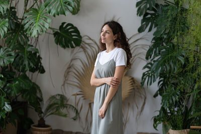 Young creative florist lady enjoy caring for houseplants in beautiful indoor garden with monstera