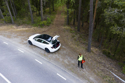 Man on side of road with broken down car