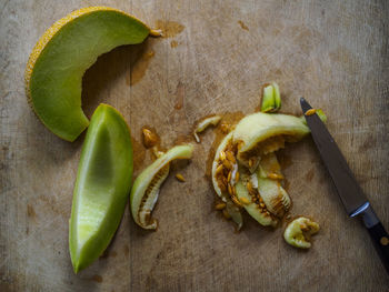 High angle view of cantaloupe by kitchen knife on cutting board