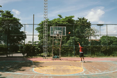 Man playing basketball hoop against sky