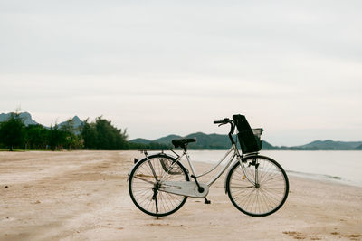 Bicycle by water against sky