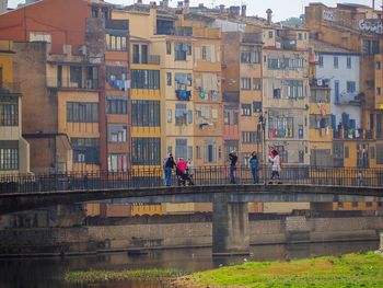People on bridge by buildings in city