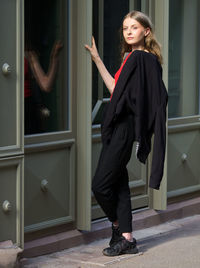 Full length of young woman standing against building