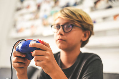 Close-up of boy playing video game at home