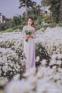 Portrait of beautiful woman standing by flowering plants