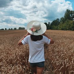Rear view of man wearing hat standing on field
