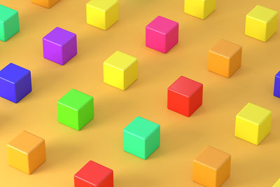 High angle view of multi colored cubes on yellow background