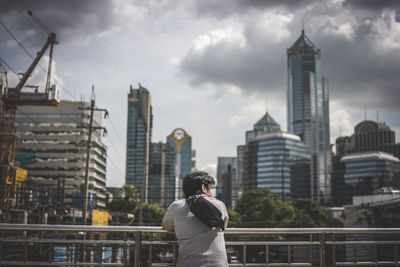 Rear view of man standing by buildings against sky